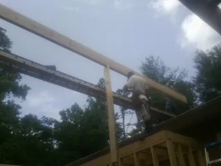 Carpenter setting a ridge beam over a new addition frame — Ice Dam Removal by Roofing Brothers in Alstead