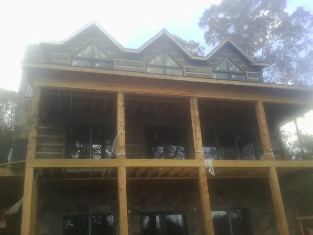 Dormers and porch framing on a large log home under construction — Roof Coating work by our crew in Alstead
