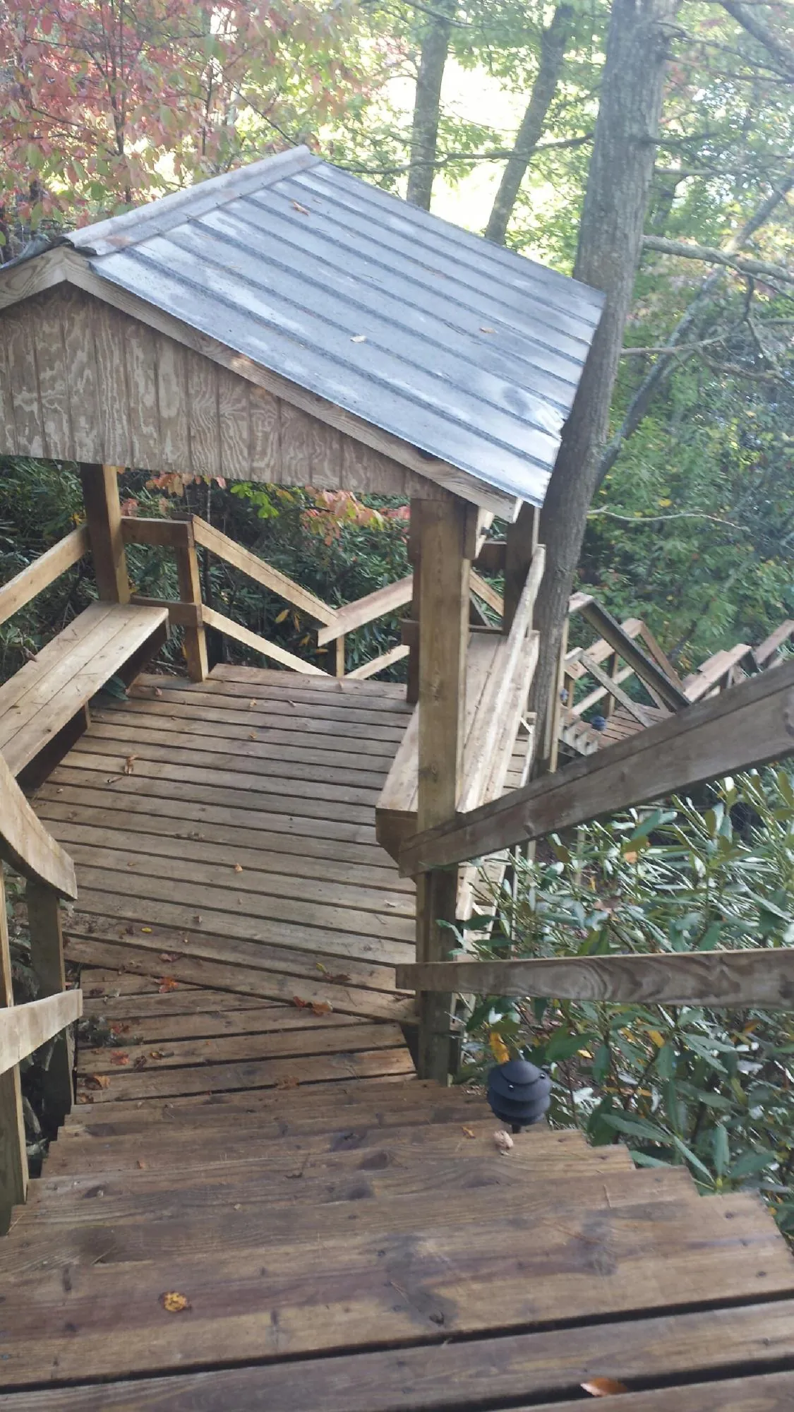 Metal roofed shelter over wooden steps on a wooded walkway — Skylight Repair & Installation work by our crew in Alstead